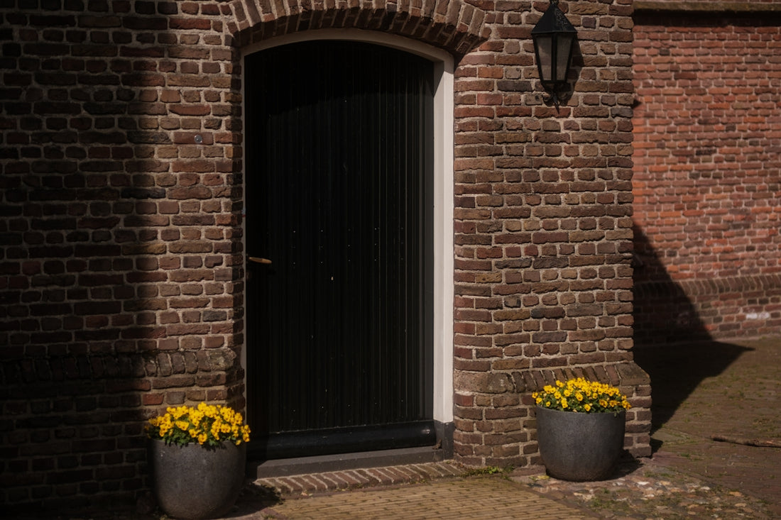 a brick building with two planters of flowers in front of it