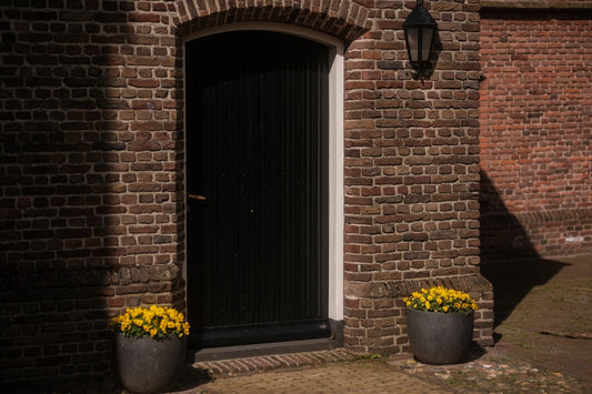 a brick building with two planters of flowers in front of it