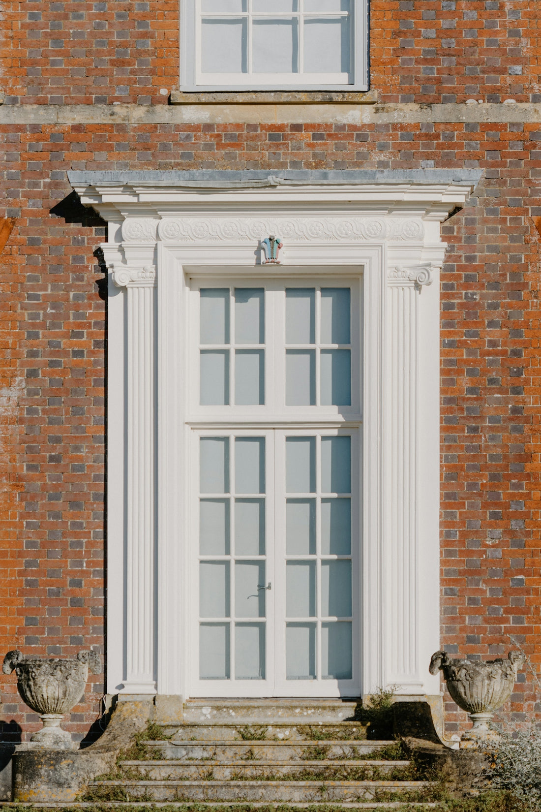 A brick building with a white window and steps