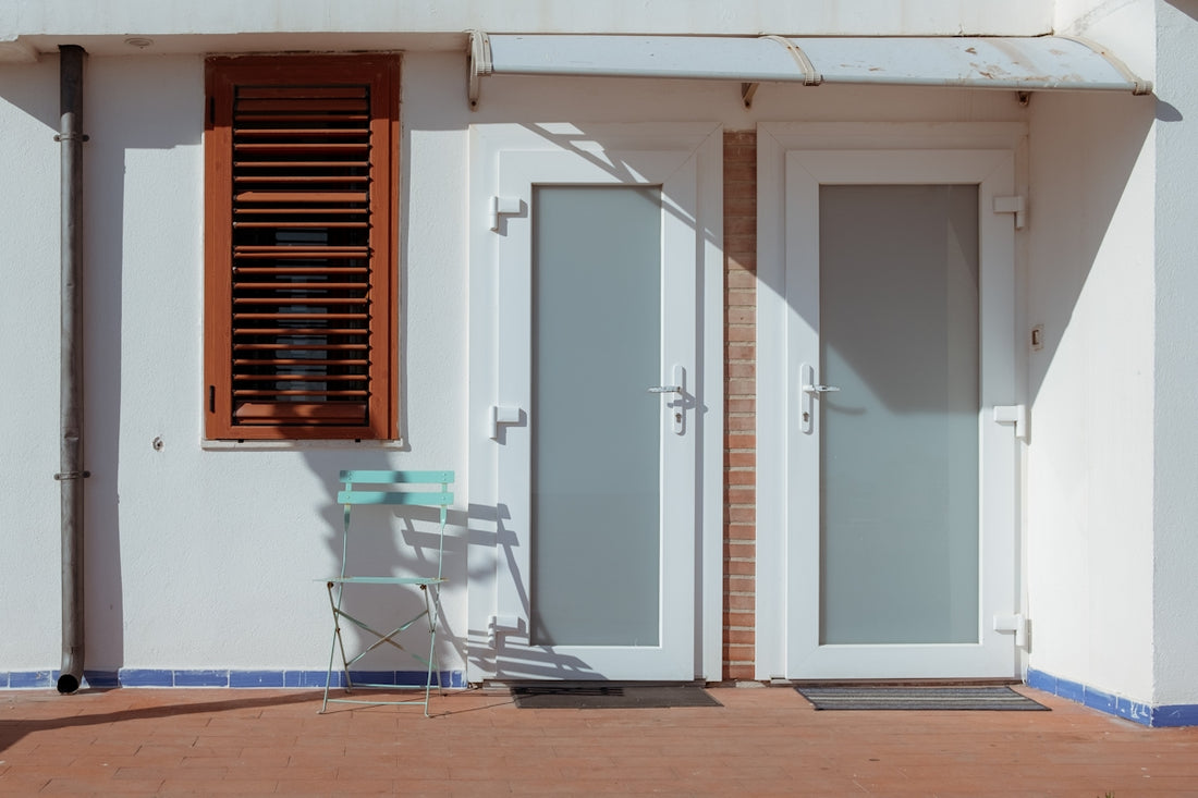 Two doors and a window on a white building.