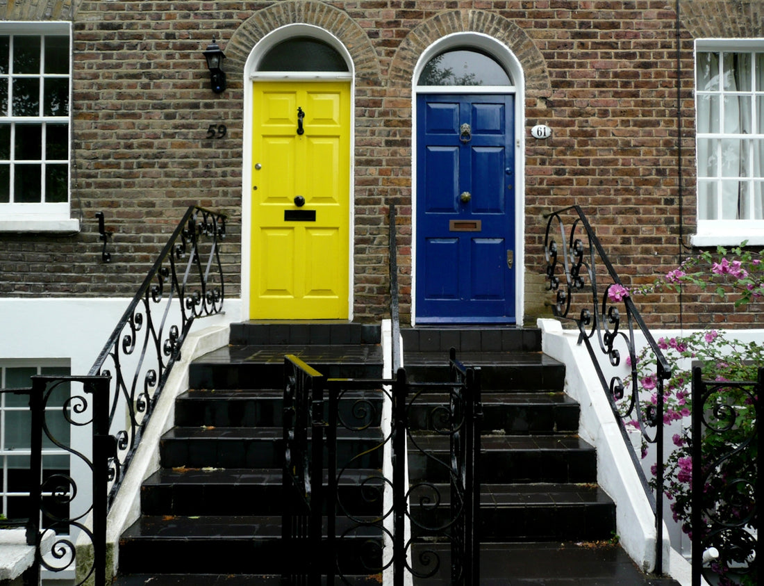Two colorful doors on brick houses with stairs