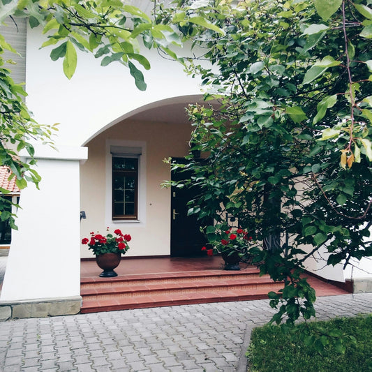 White building entrance with red flowers and greenery
