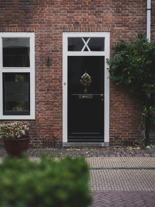 A black door on a brick house with a wreath.