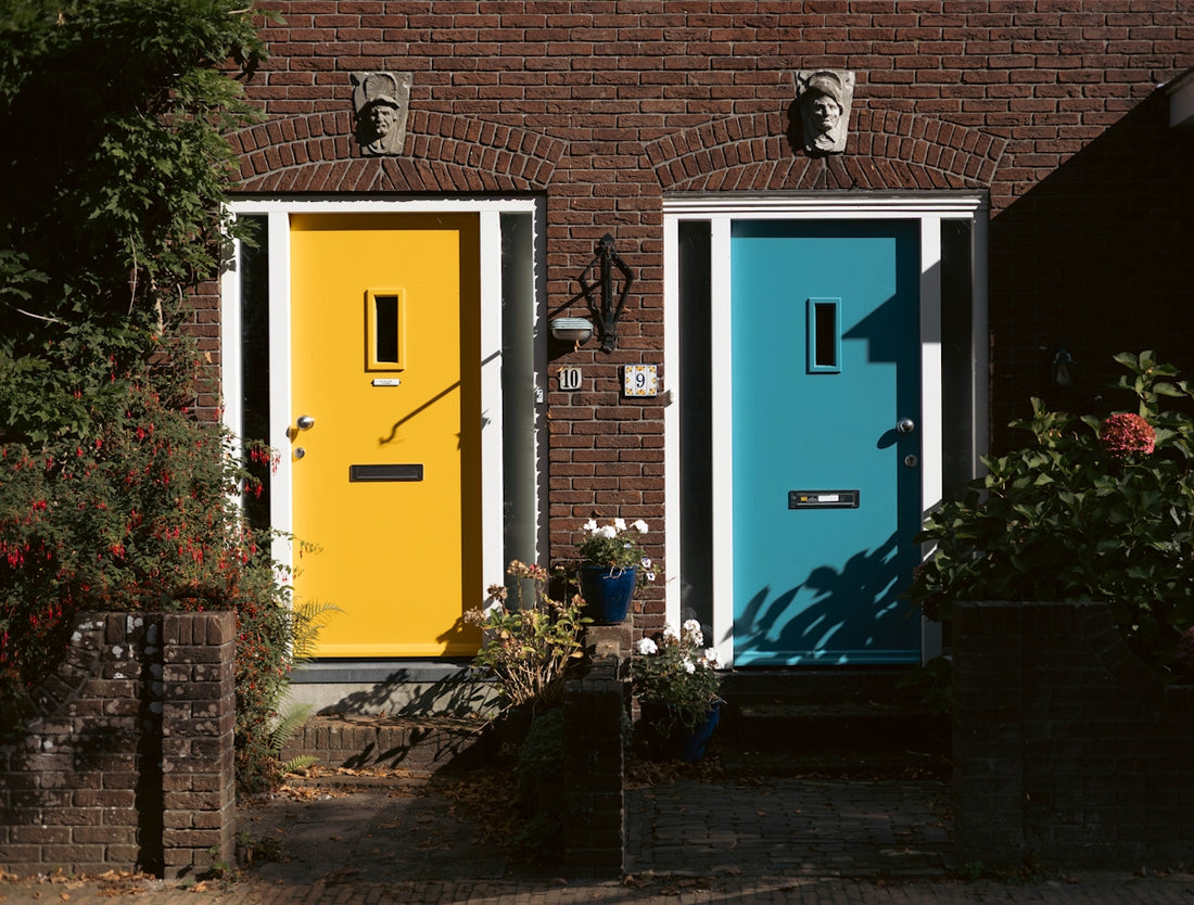 Two colorful doors, yellow and blue, on brick houses.