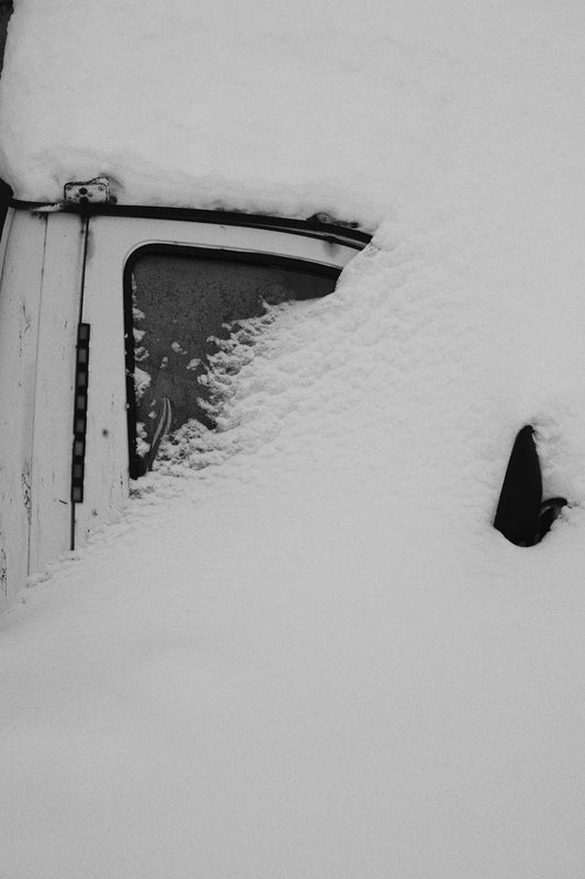 A white vehicle covered in deep snow