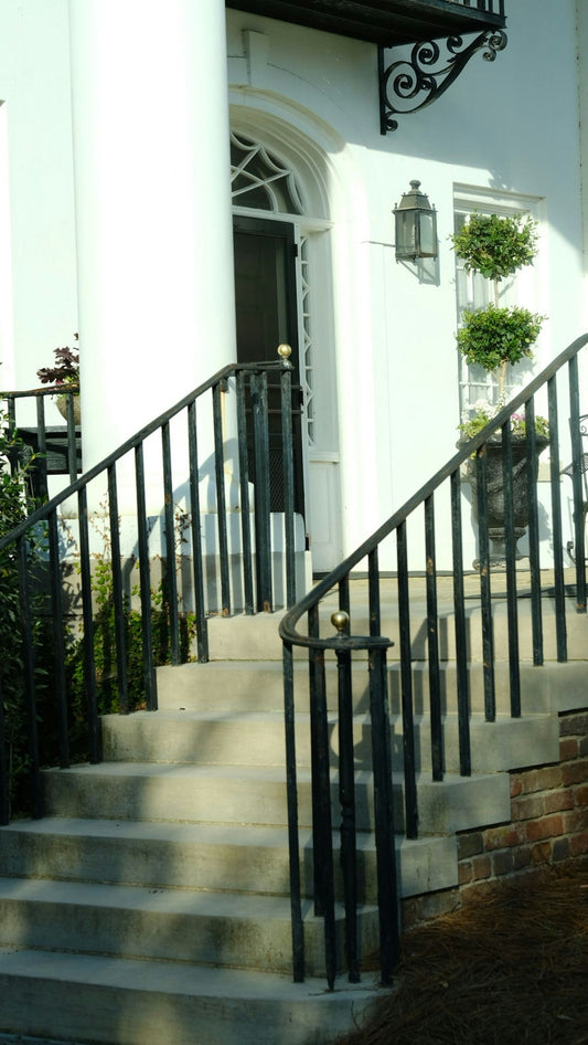 White house with stone steps and black railings.
