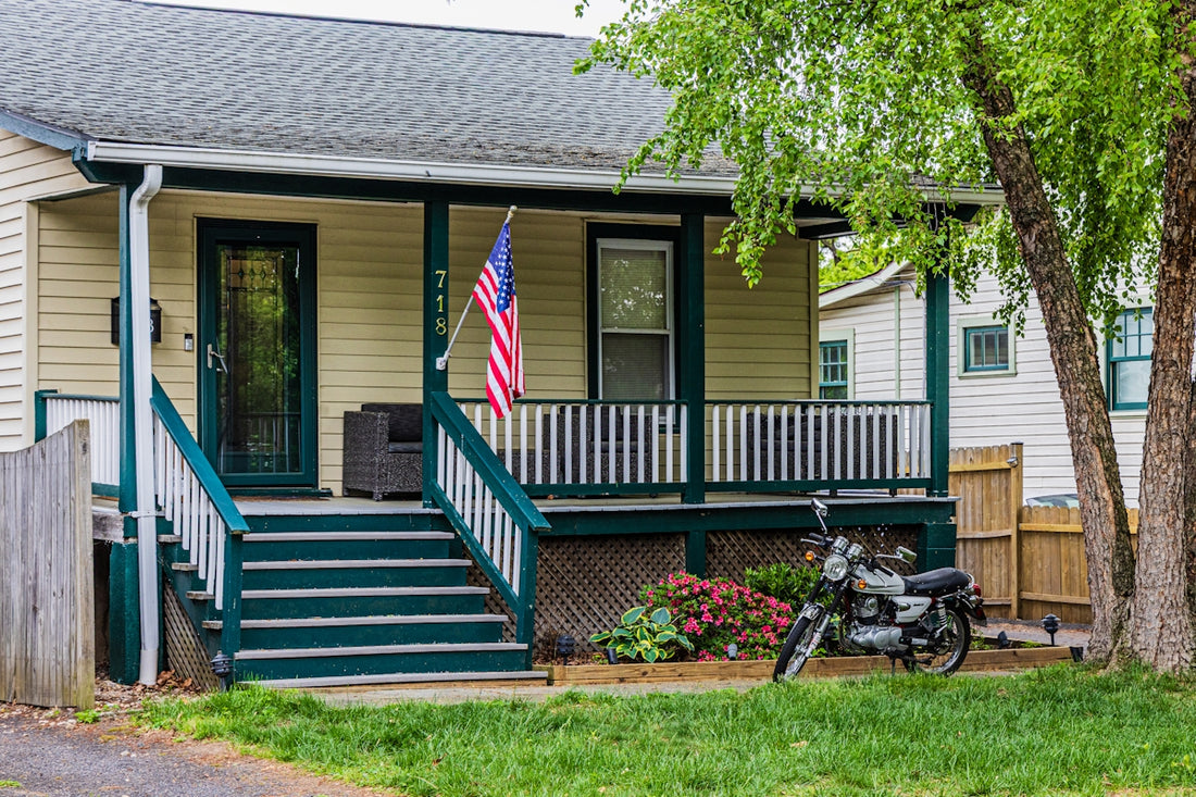 A modest house with a porch and a motorcycle.