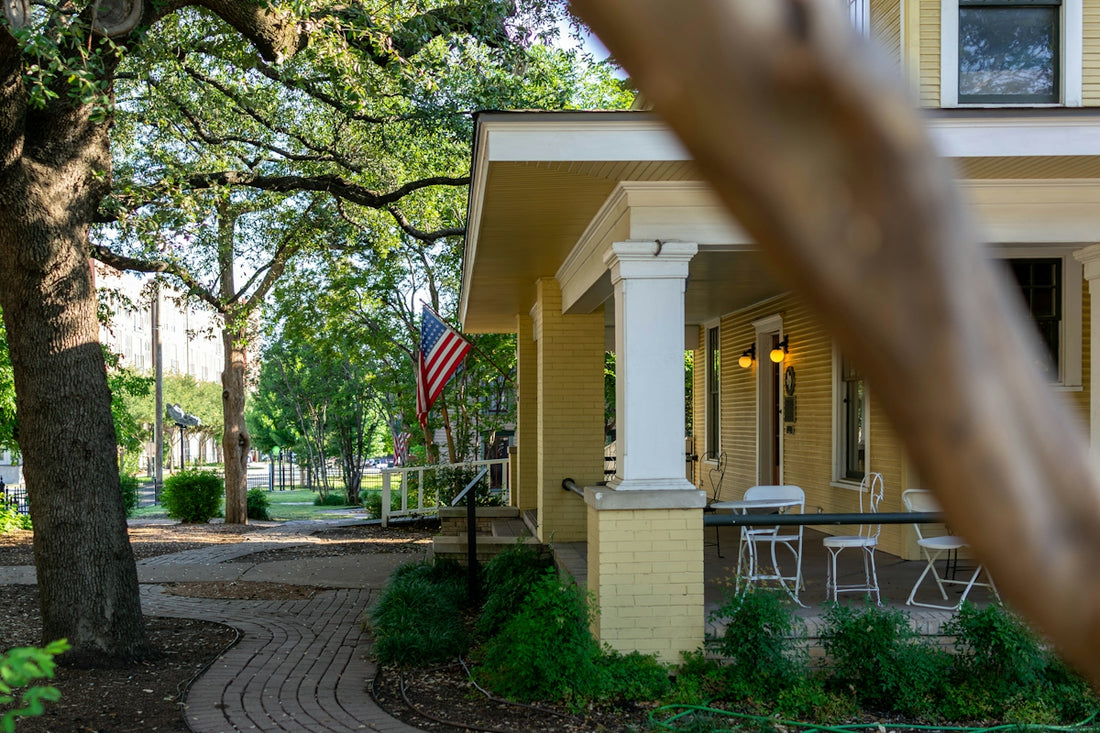 Yellow house with a porch, american flag, and brick pathway