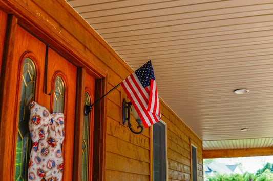 An american flag hangs proudly on a wooden porch.