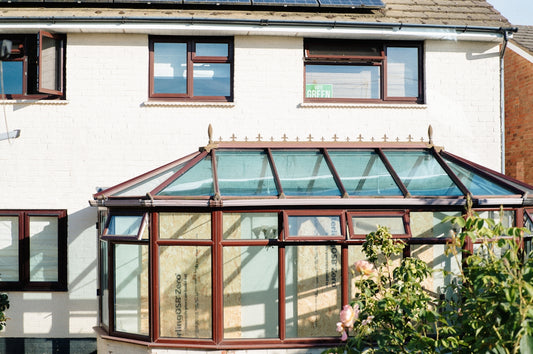 White house with brown conservatory and windows