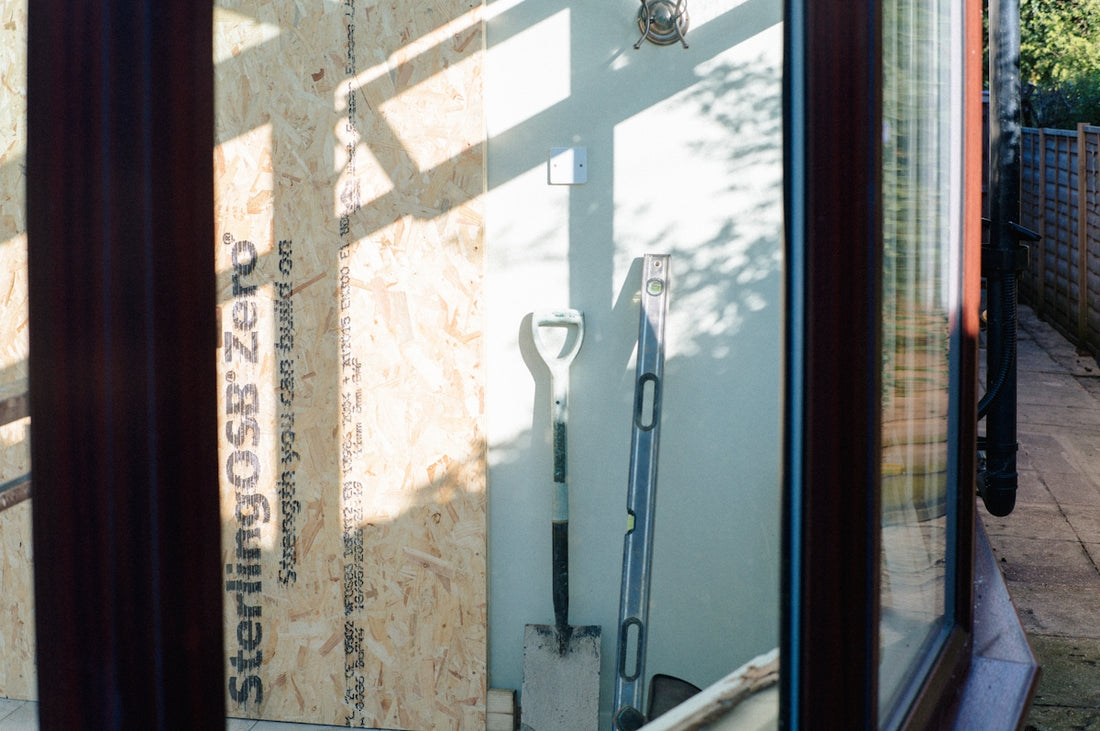 Shovel and tools leaning against osb wall in sunlight