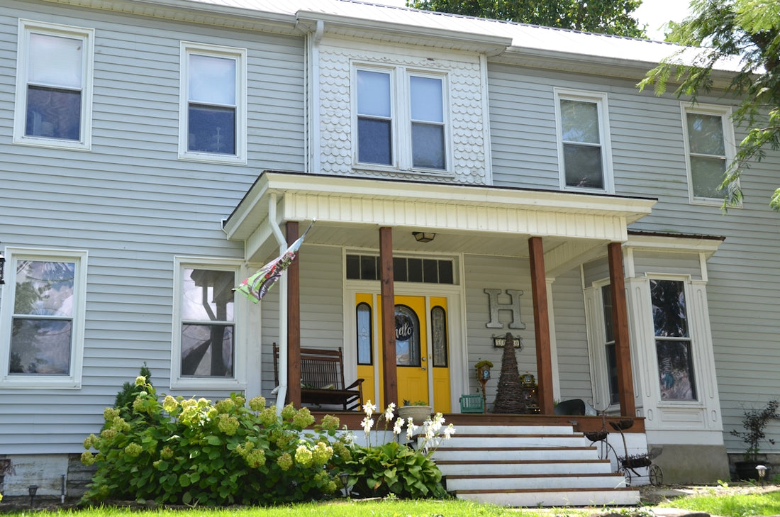 A two-story house with light grey siding and a bright yellow front door