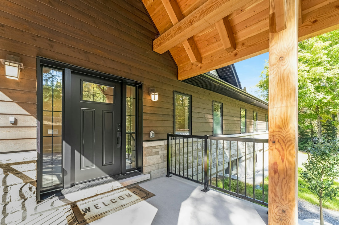 A black front door with a welcome mat on a wooden porch