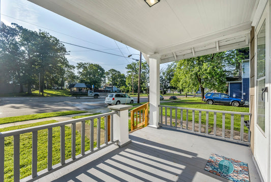 A view from a covered porch overlooking a suburban street with parked cars